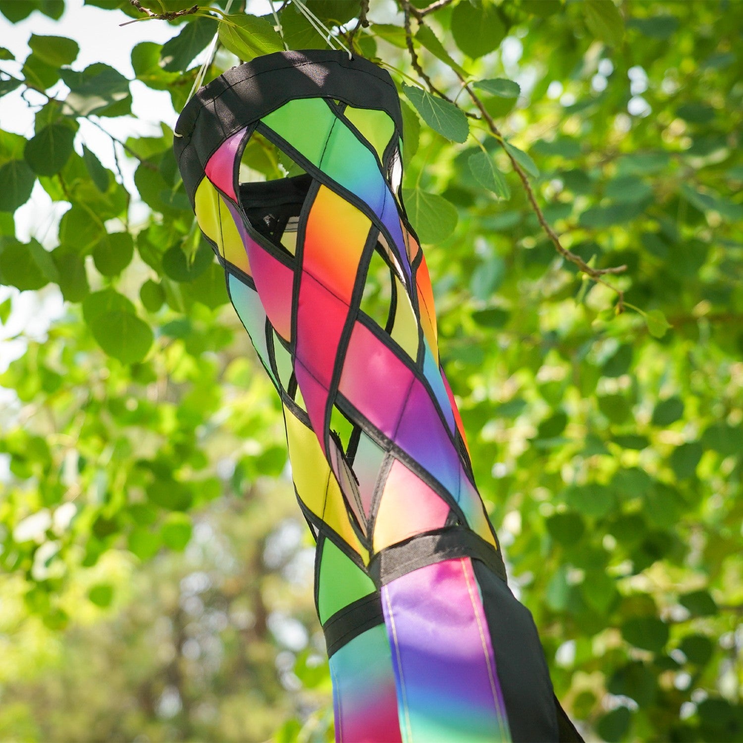 Jewel Diagonal Weave 40-inch windsock with bright jewel colors and black tails, fluttering in a light breeze, displayed in a garden area.
