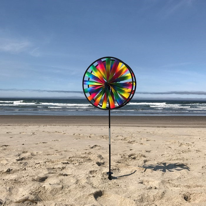 Kaleidoscope Double Wheel Spinner featuring rainbow colors and durable fiberglass frames, spinning in a garden setting on a sunny day.