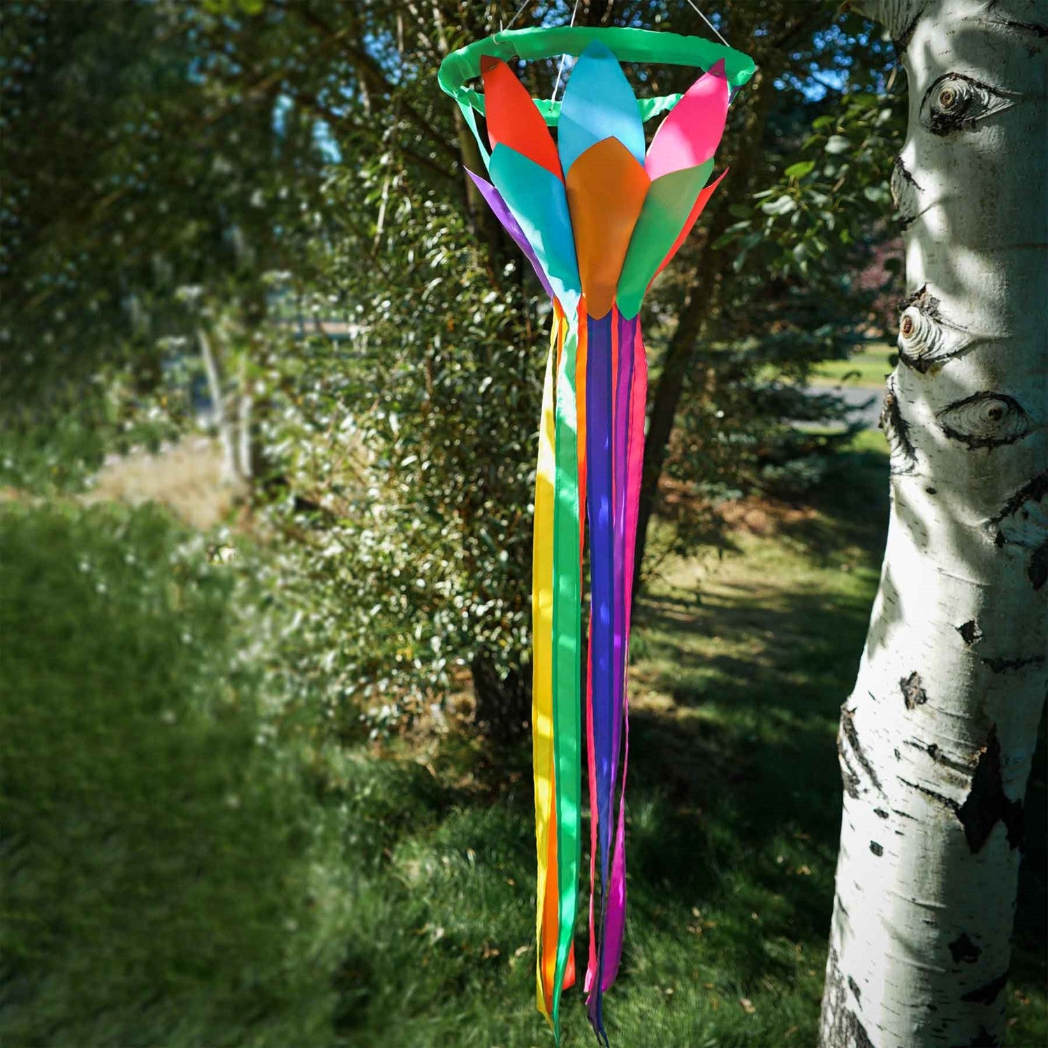 Kaleidoscope 38-inch Lotus Flower Windsock featuring bright petals and flowing rainbow tails, displayed outdoors in a garden setting.
