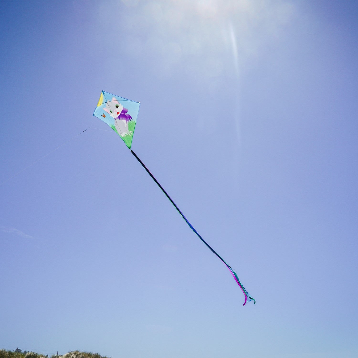 Colorful Kitten 30" Diamond Kite with a cheerful kitten design soaring against a bright blue sky, with tails fluttering in the wind.