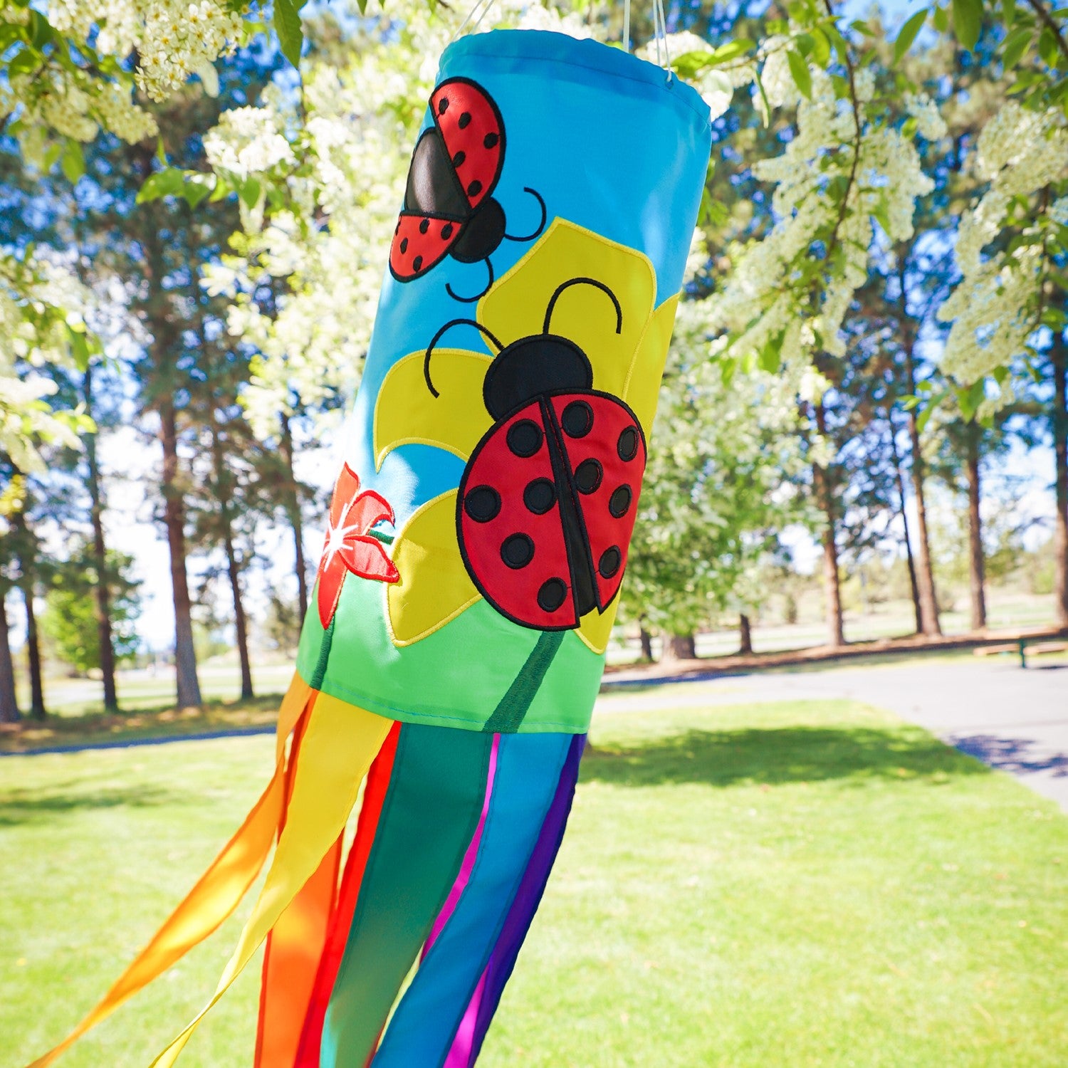 A stunning Ladybug Flower 40" windsock featuring vibrant colors and detailed appliqued graphics, fluttering gracefully with eight coordinating tails.