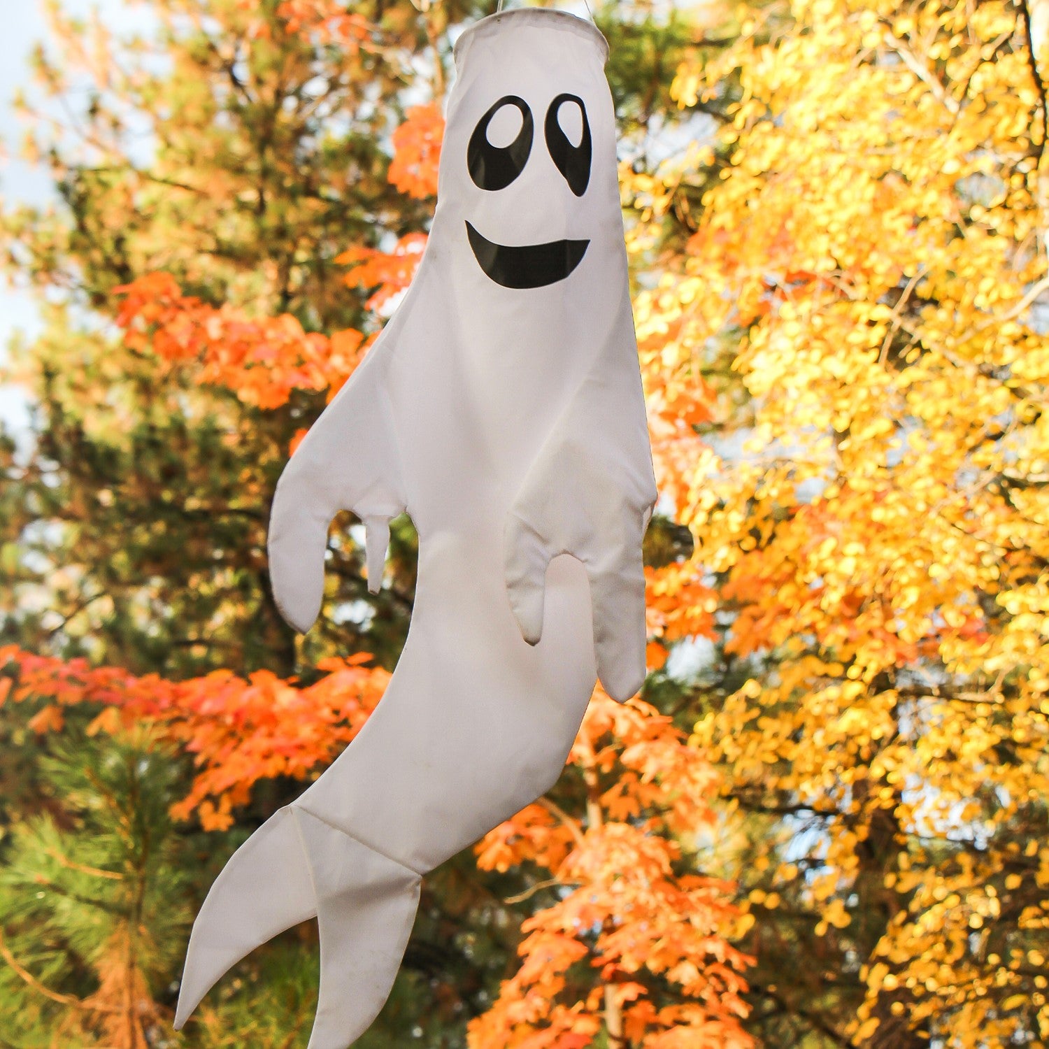 Large Ghost Windsock with a grinning face, made from heavy-weight polyester, fluttering in the breeze, perfect for Halloween and fall decorations.