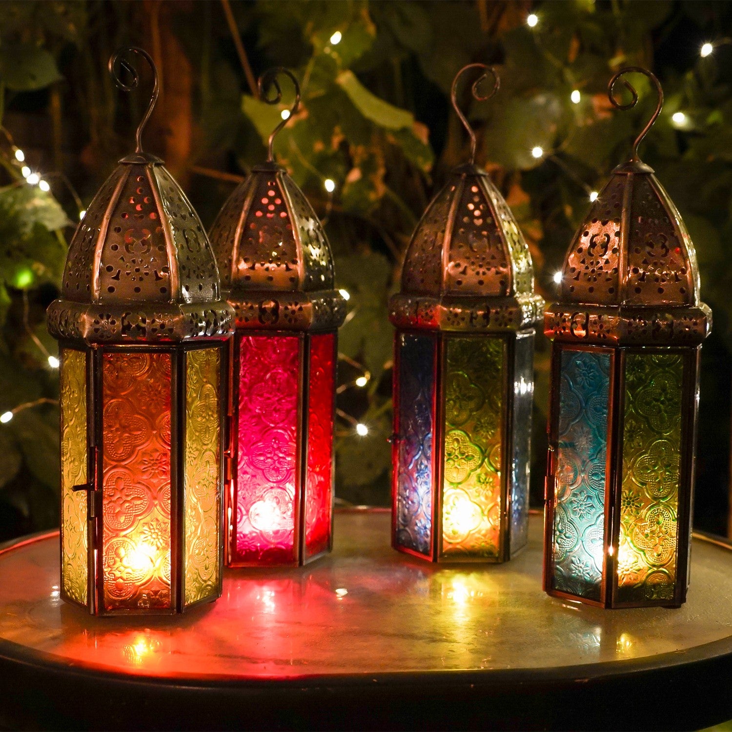 Large Orange & Yellow Hex Glass Tealight Lantern with stamped glass panels and metal accents hanging in an outdoor garden setting.