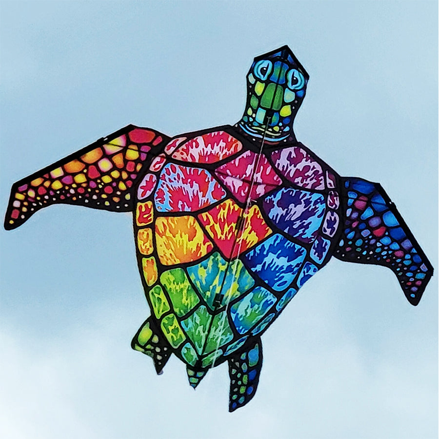 Large Sea Turtle Kite in rainbow colors displayed in the sky, measuring 65x54 inches, designed for stable and vibrant flying.