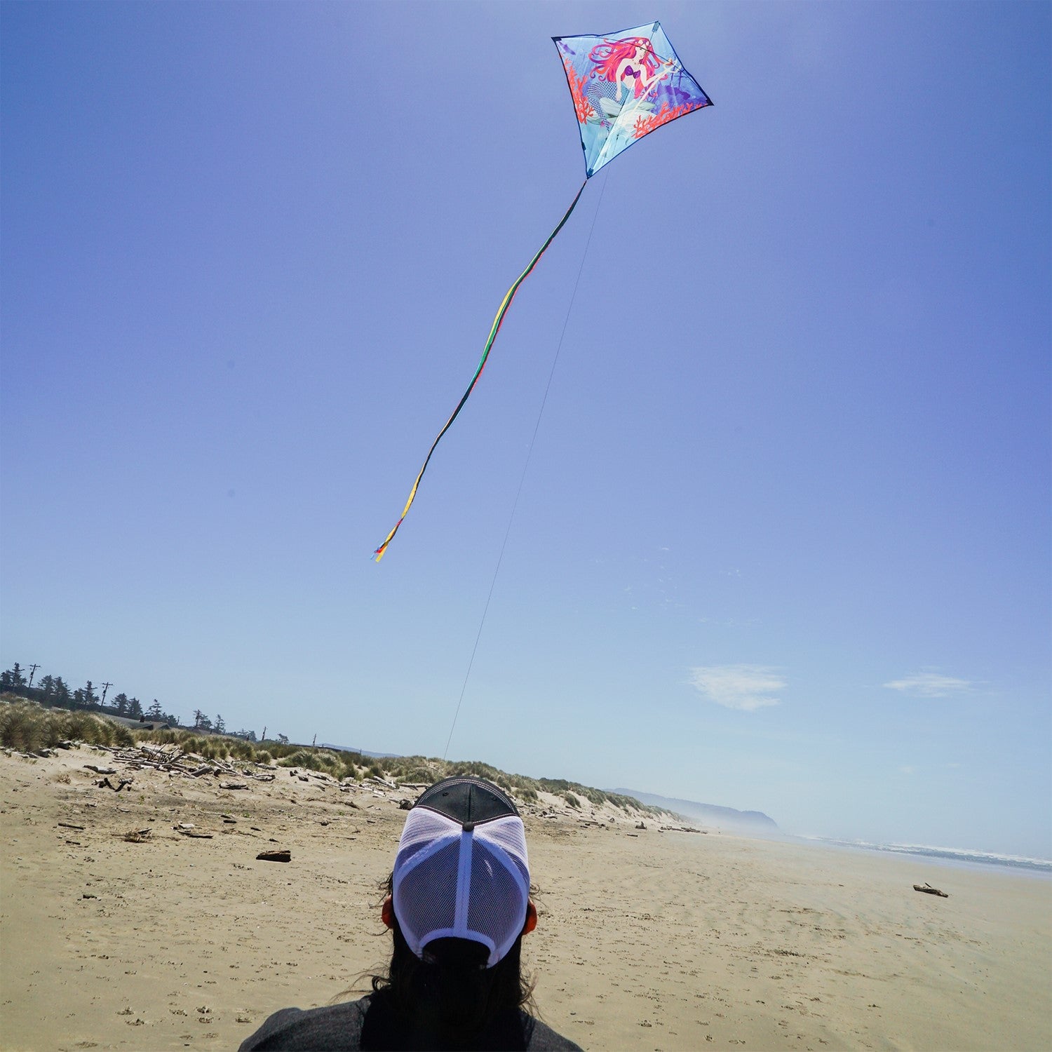 Mermaid 30" Diamond Kite flying in a clear blue sky, featuring bright colors and detailed graphics, ideal for kids and adults alike.