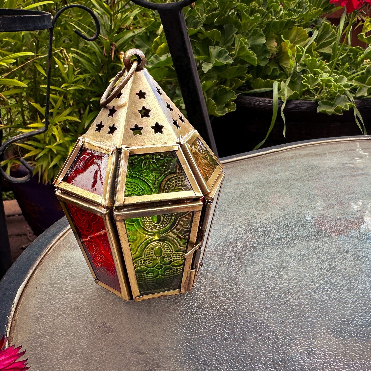 Mini Red, Yellow & Green Hex Glass Tealight Lantern showcasing vibrant colors with intricate metal accents, designed for tealights, hanging in an outdoor setting.