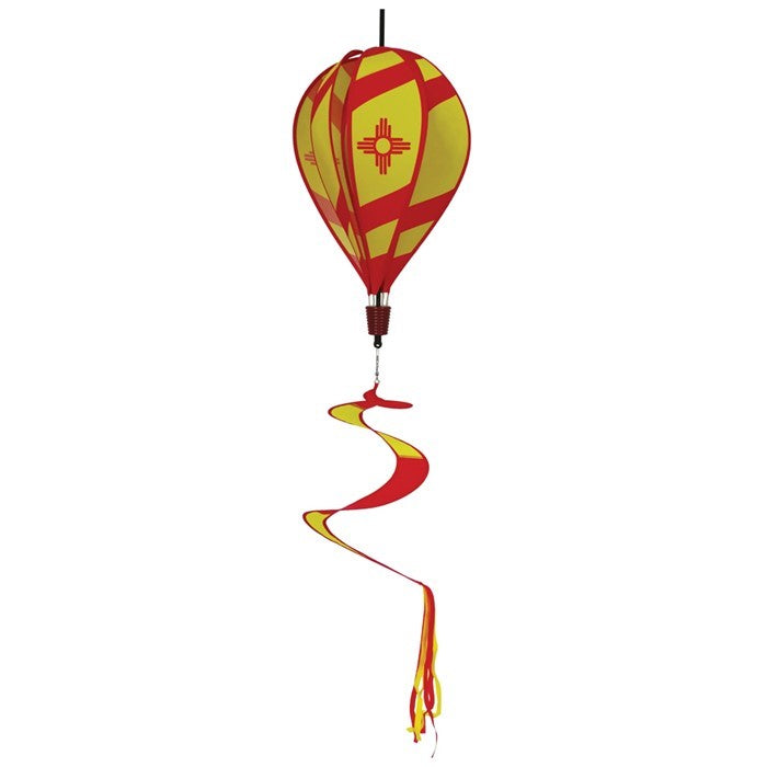 Vibrant New Mexico hot air balloon spinner with red stripes and sun design, gracefully spinning in an outdoor garden setting.