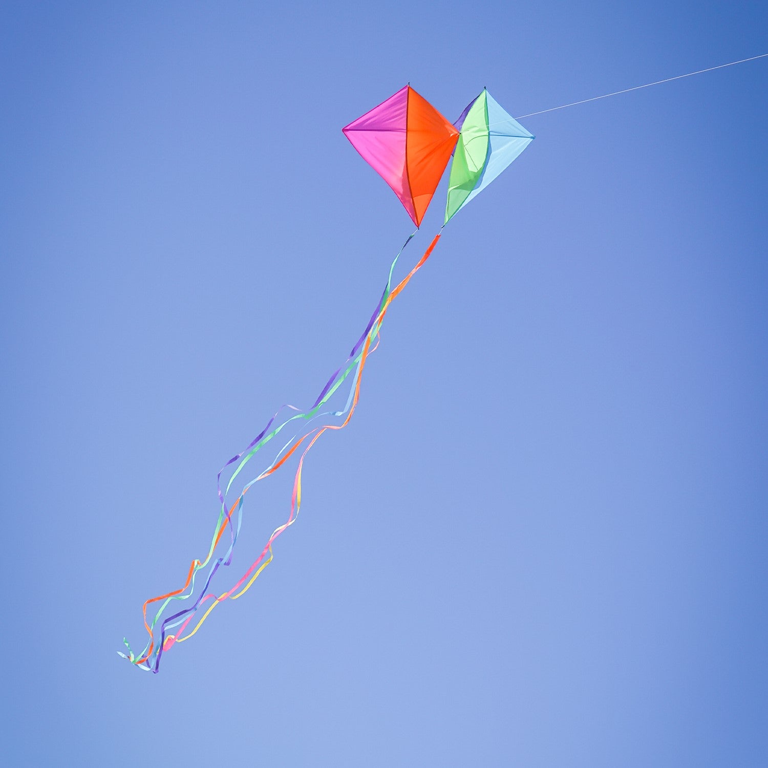 Pacific Dancing Diamonds Kite with colorful diamond panel design soaring in the sky, featuring attached tails and displayed at a kite flying event.