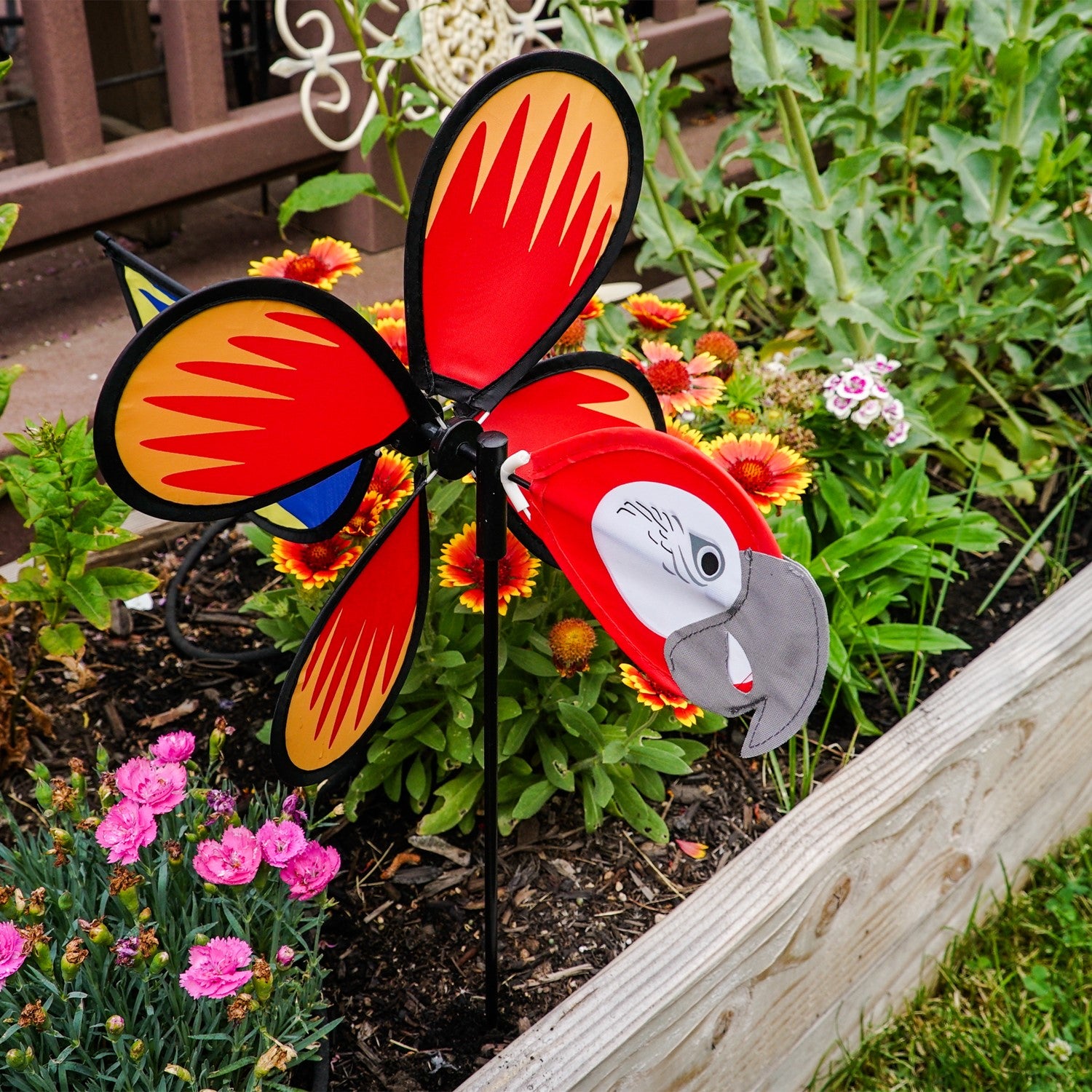 Parrot Baby Spinner featuring bright colors and detailed graphics, spinning easily on a 17-inch fiberglass pole in a garden setting.
