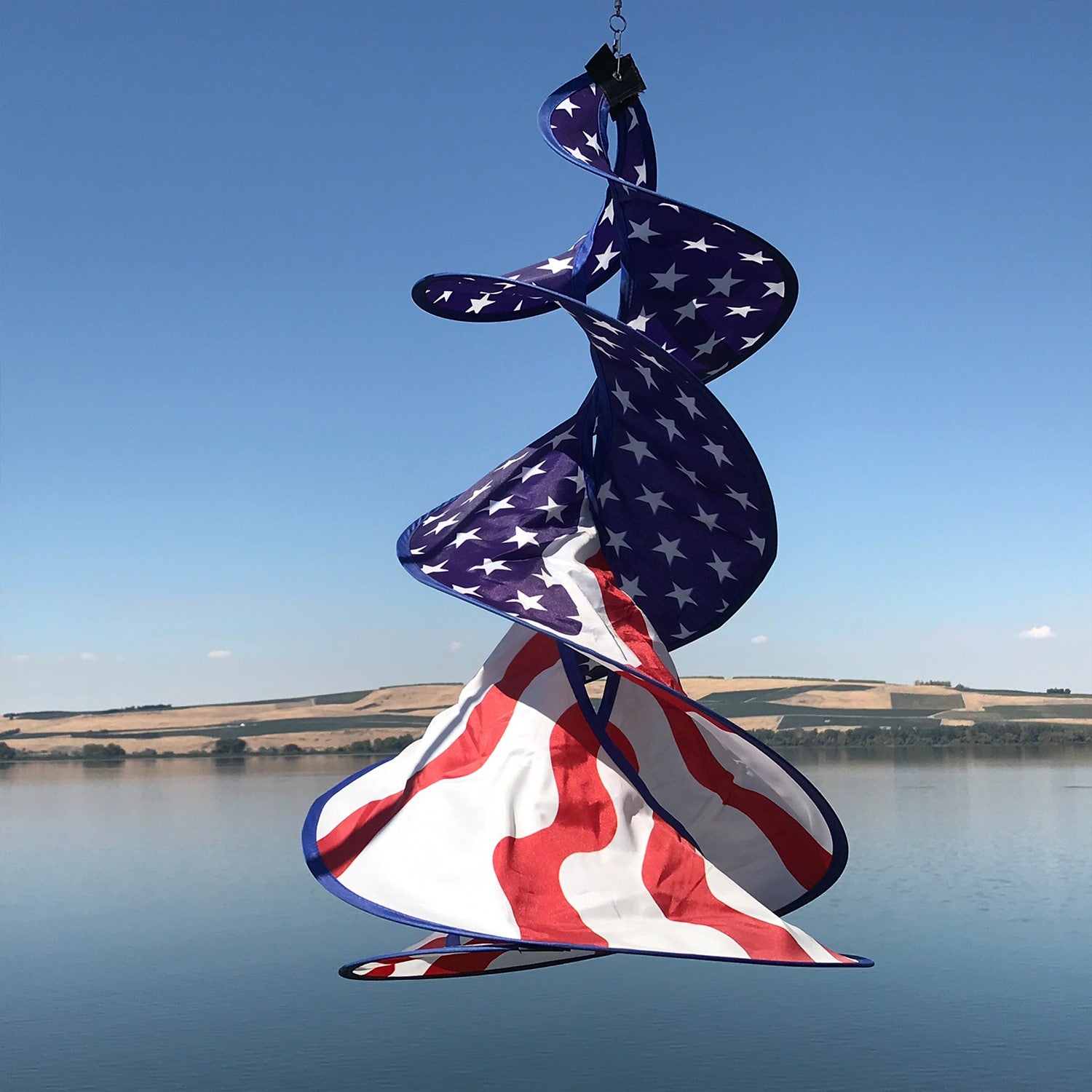 Patriot Spin Duet double spinner decoration featuring red, white, and blue stars and stripes design hanging outdoors in a garden setting.