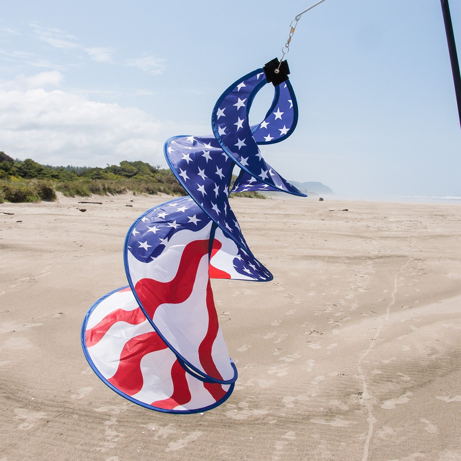 Patriot Spin Duet double spinner decoration featuring red, white, and blue stars and stripes design hanging outdoors in a garden setting.