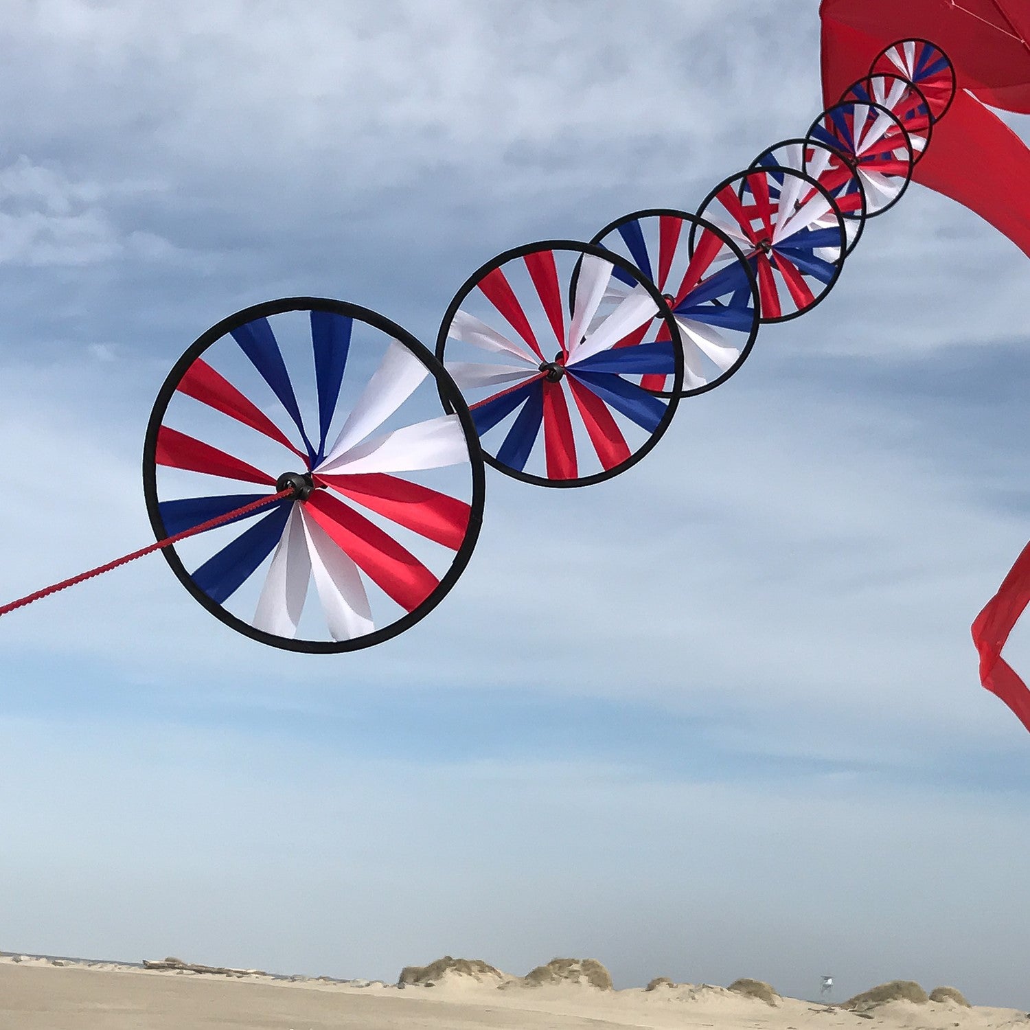 Patriot Spinner Wheels on String with red, white, and blue spinning wheels, hanging decor fluttering in the breeze in a garden setting.