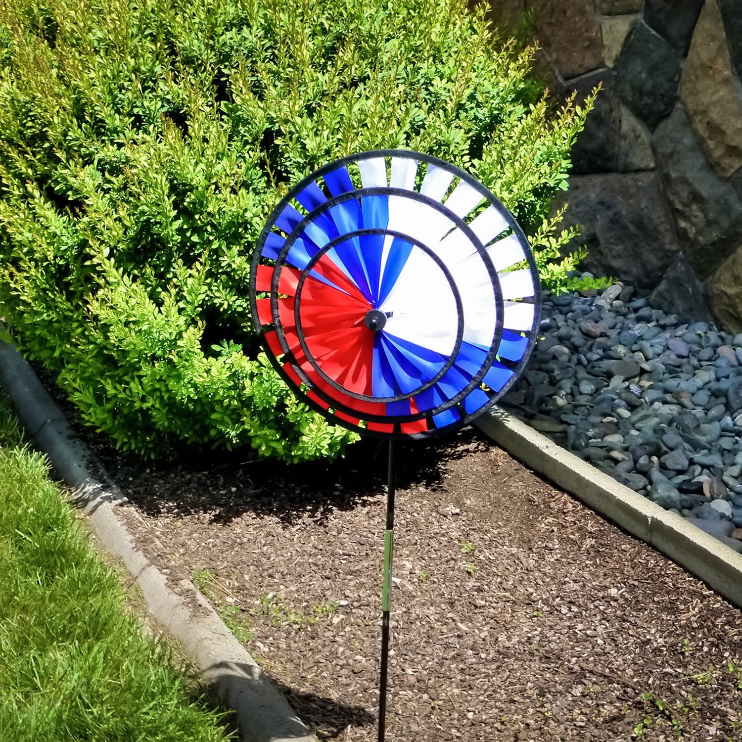 Patriot Triple Wheel Spinner featuring red, white, and blue wheels spinning in the breeze, set on a decorative garden stake.