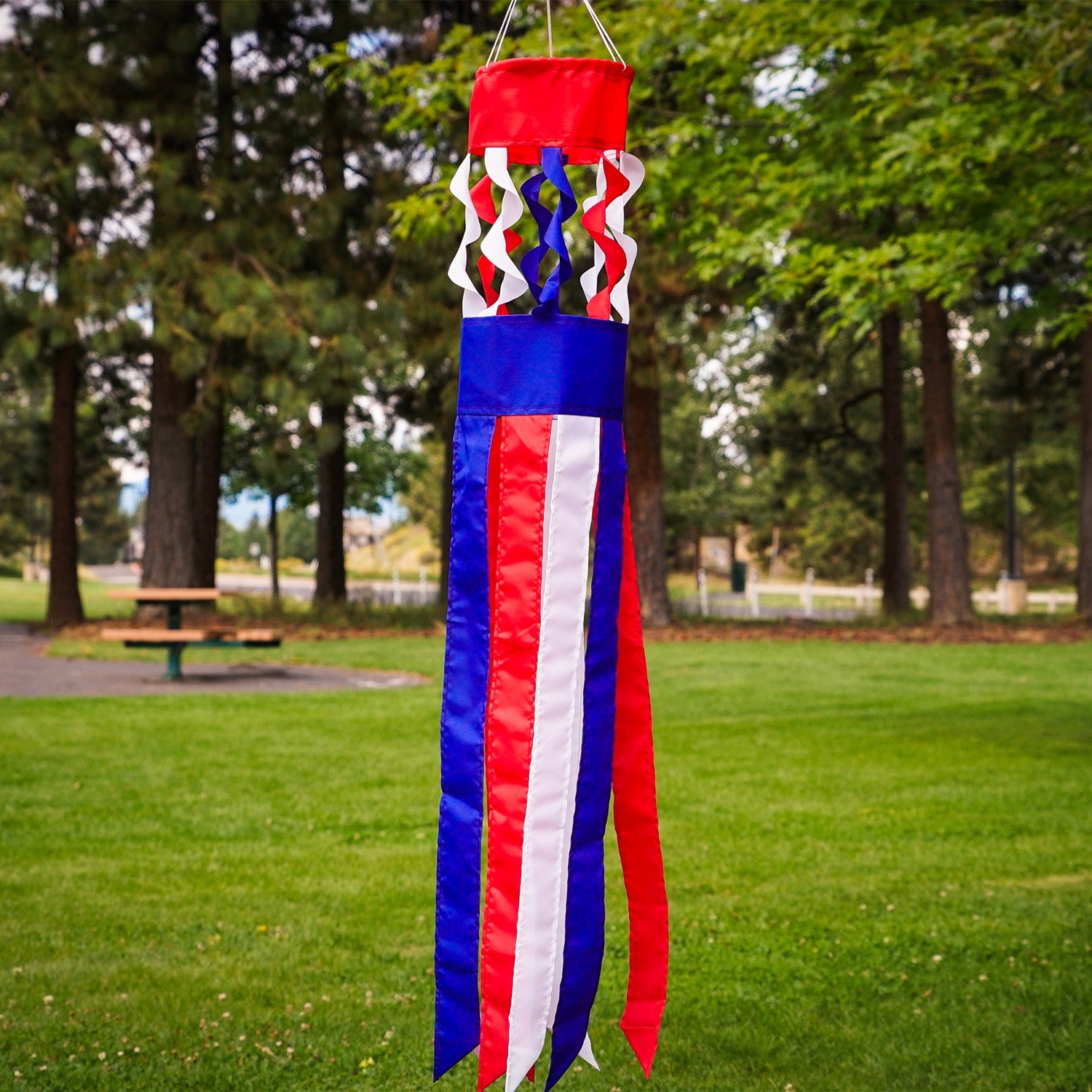 Patriot Twistair windsock featuring red, white, and blue colors with twisted curls, elegantly displayed in a garden setting.
