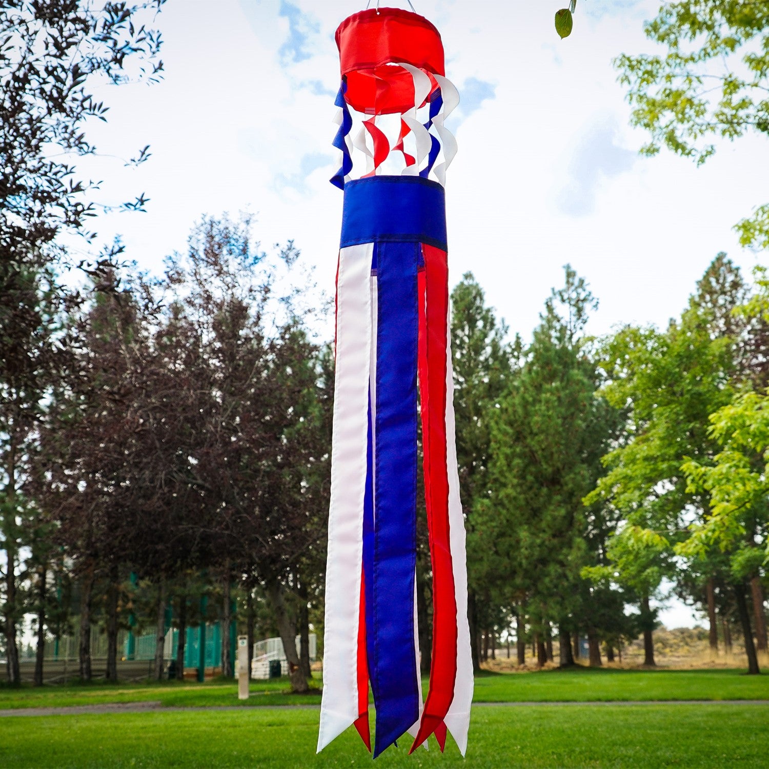 Patriot Twistair windsock featuring red, white, and blue colors with twisted curls, elegantly displayed in a garden setting.