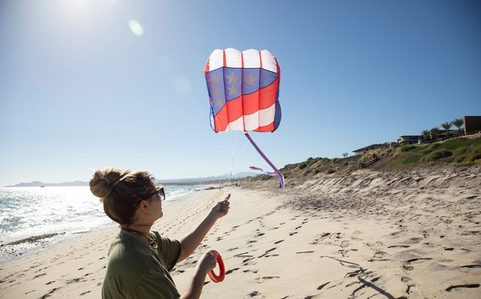 7.5 Patriot Wave Air Foil Kite soaring in the sky with red, white, and blue colors and stars, showcasing its lightweight design and beauty.