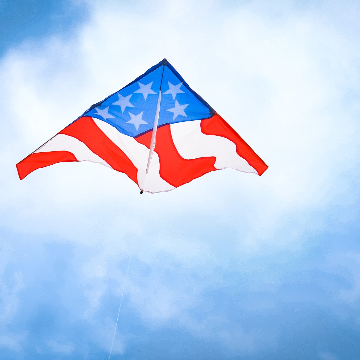 Patriotic 57 inch Delta Kite with red, white, and blue stars and stripes design soaring high in the blue sky against a sunny backdrop.