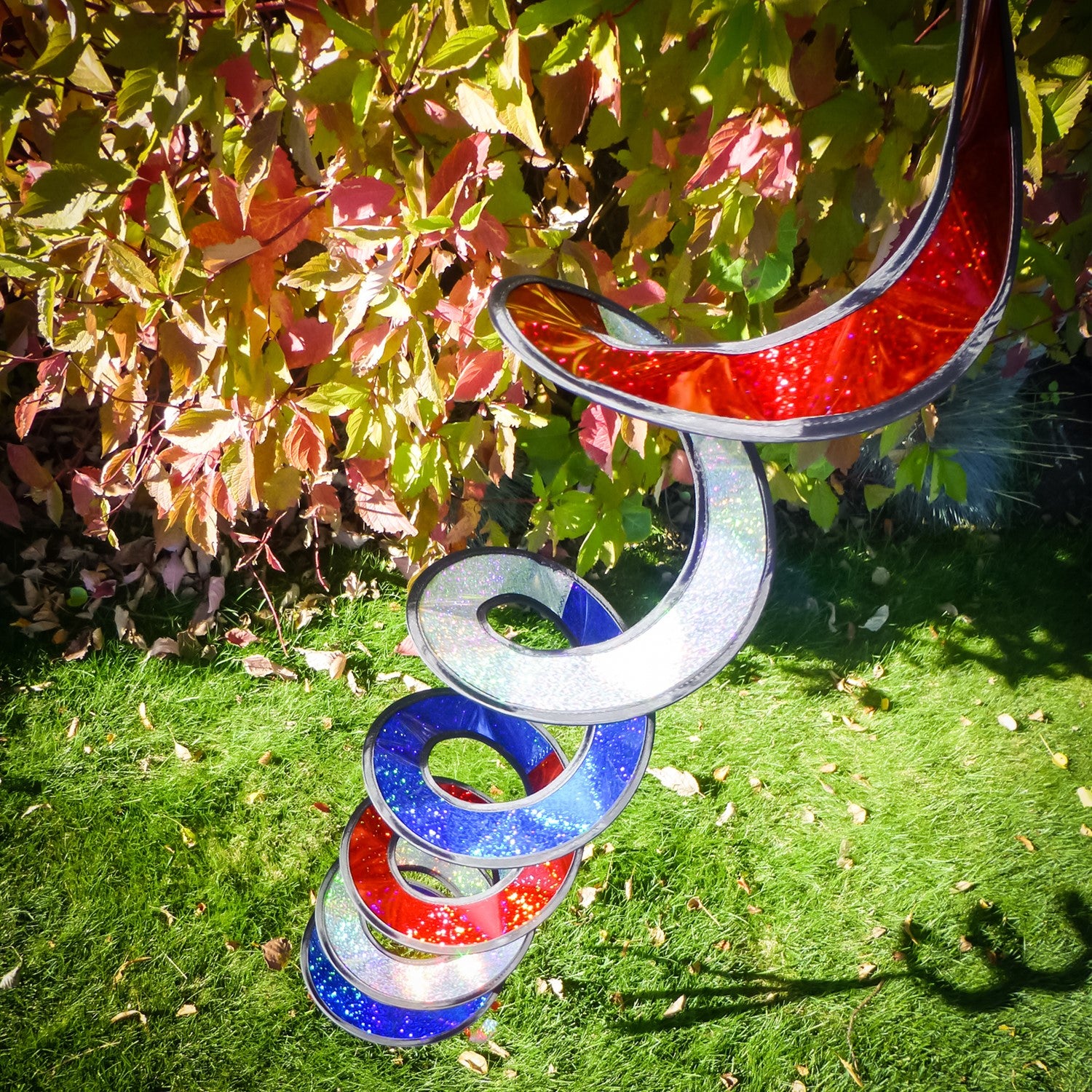 Patriotic Sparkle Curlie in red, white, and blue waving in the breeze, showcasing its 48-inch dazzling Mylar design with tails.