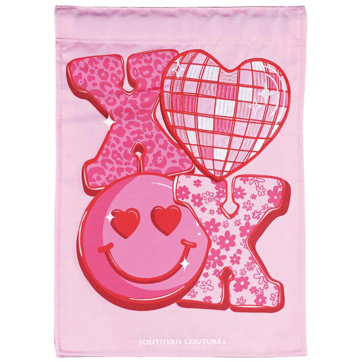 Pattern XOXO double applique garden flag featuring intricate fabric designs in outdoor setting, displayed on a flagpole in a garden.