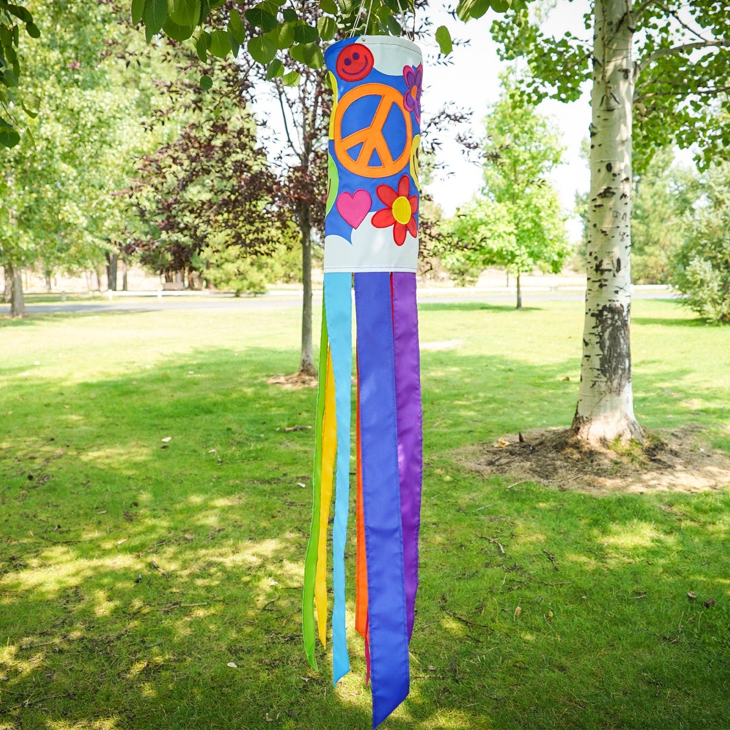 Peace, Love & Happiness 40-inch windsock with psychedelic designs and colorful tails, fluttering in the breeze outdoors.