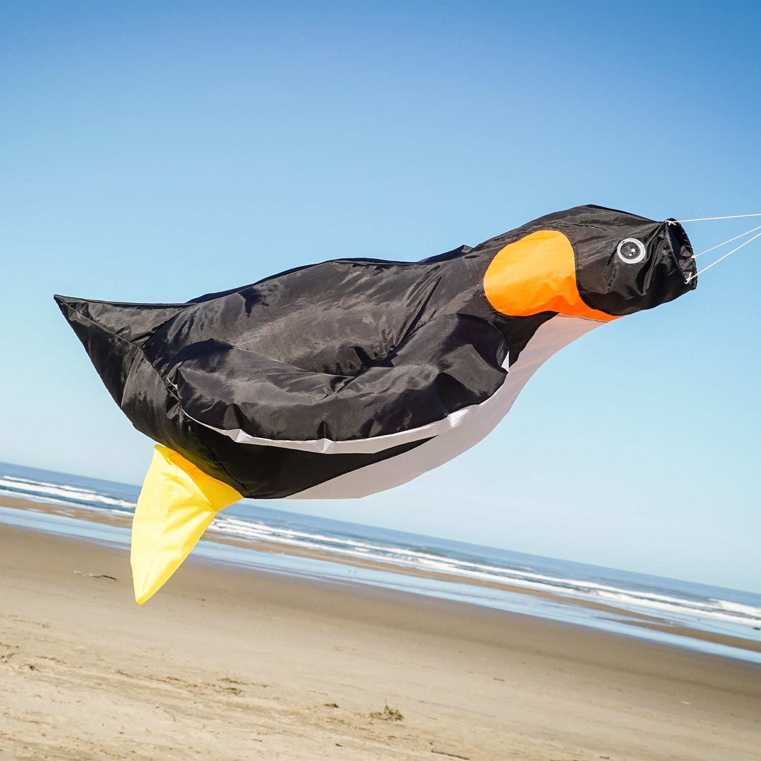 Penguin Big Breeze WindsockTM displayed outdoors showcasing its vibrant colors and 3D body, filled with air as it sways in the breeze.