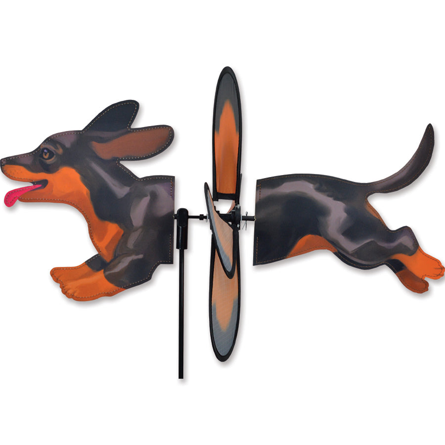 Petite Spinner featuring a black and tan dachshund design spinning gently in an outdoor garden setting.