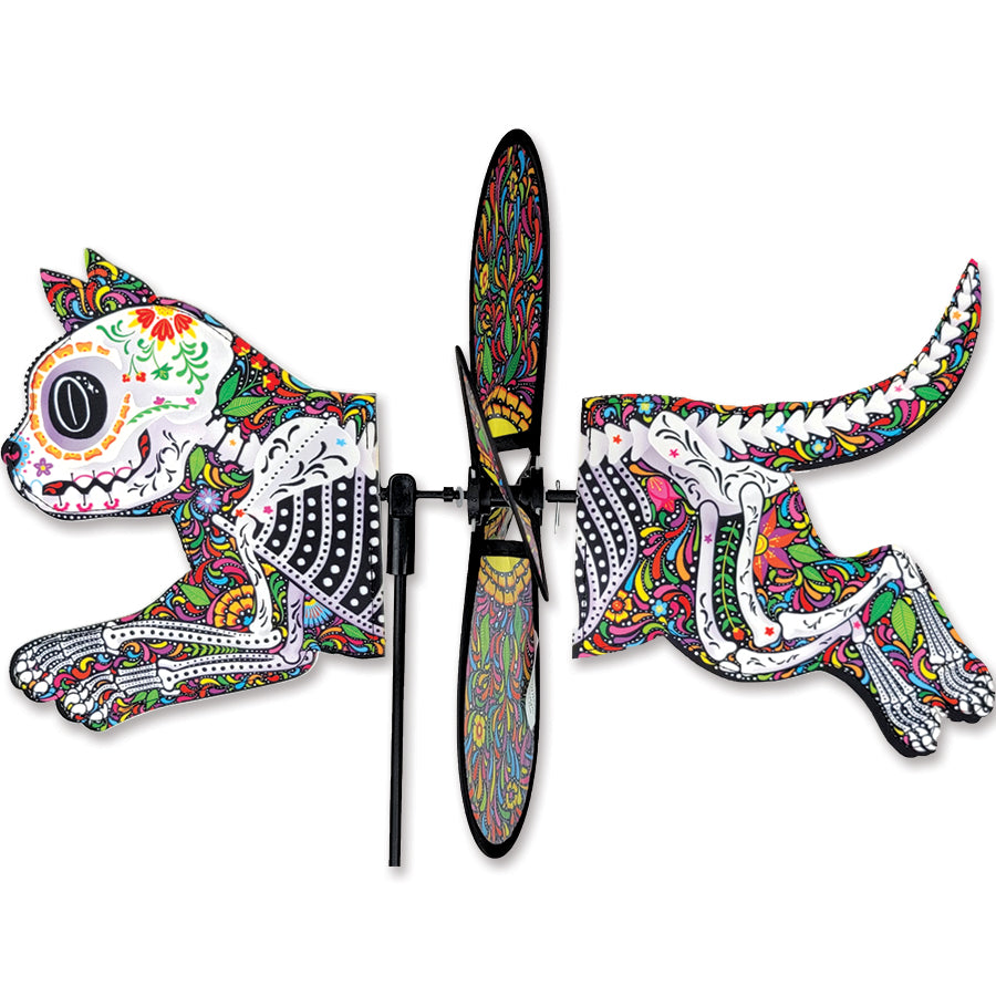 Petite Spinner - Day of the Dead Cat, featuring colorful designs, twirling gently in a garden setting, adding festive charm to outdoor decor.