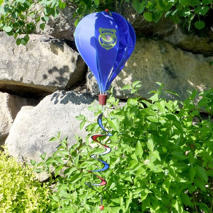 Police Hot Air Balloon decoration with Police Service logo on a blue background, spinning in the breeze, displayed in a garden setting.