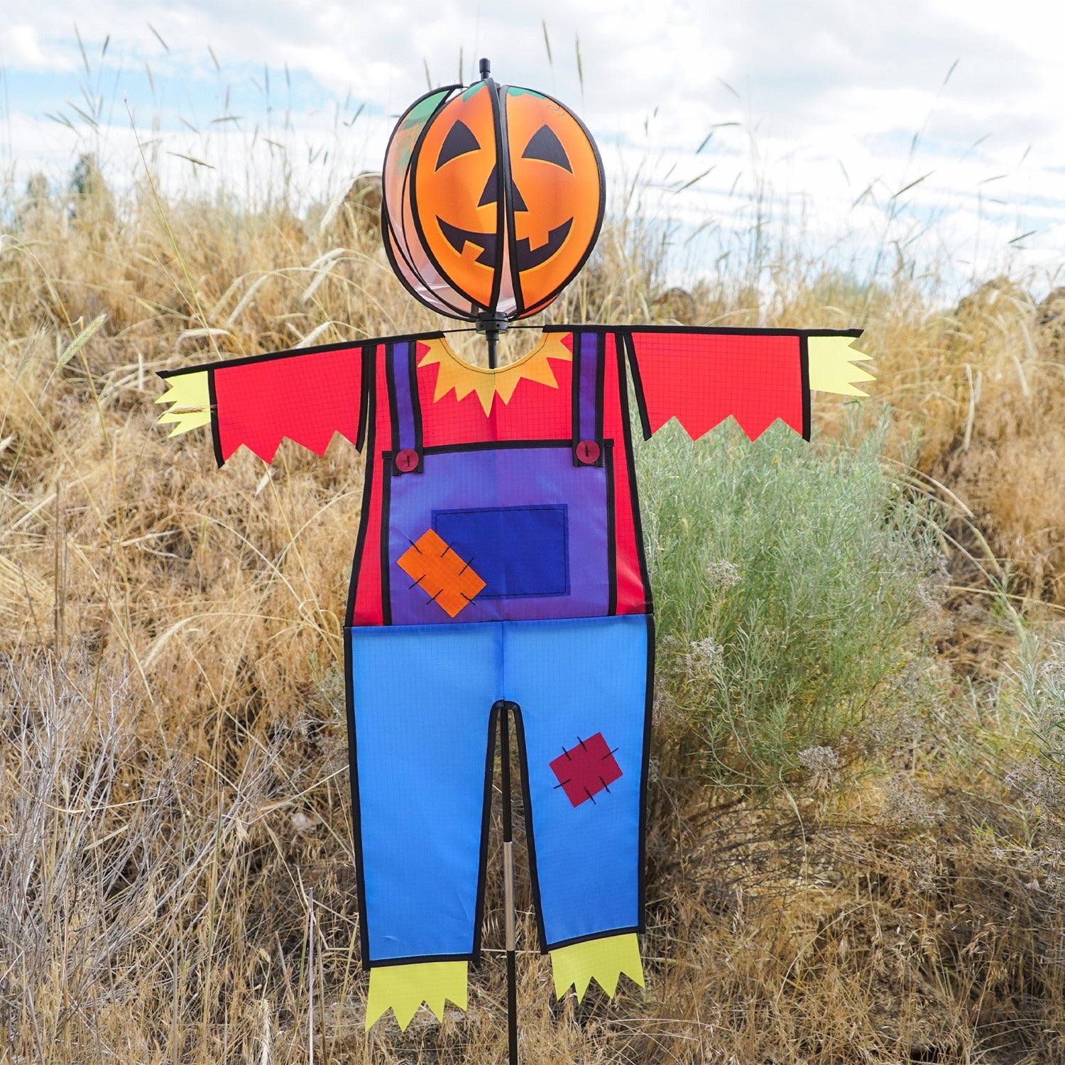 Pumpkin Scarecrow Ground Ball Spinner featuring vibrant pumpkin head and colorful attire, standing tall in a garden setting.