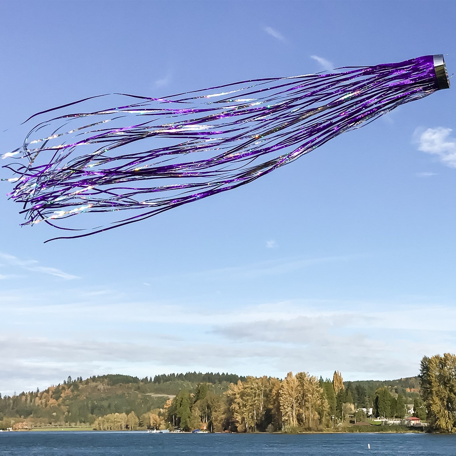 Colorful Purple 51-inch Mylar Windsock with holographic design fluttering in a gentle breeze in a well-kept garden.
