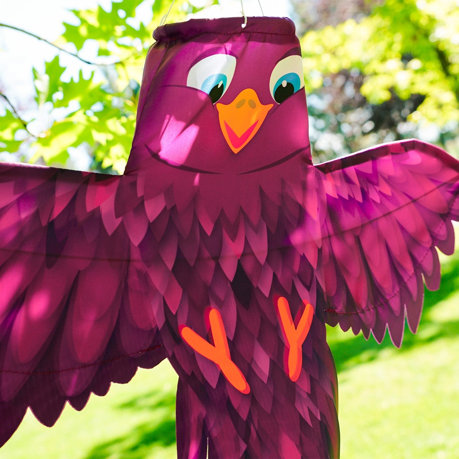 Colorful Purple Bird Windsock with spread wings fluttering in a gentle breeze, showcasing vibrant purple hues in an outdoor setting.