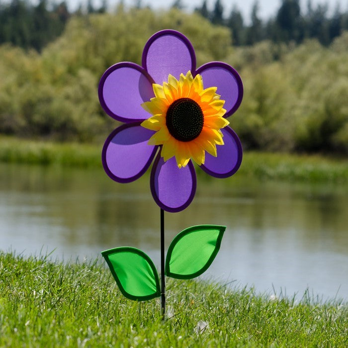 Vibrant 12-inch Purple Sunflower Spinner with purple petals and green leaves displayed in an outdoor garden setting, spinning gently in the breeze.
