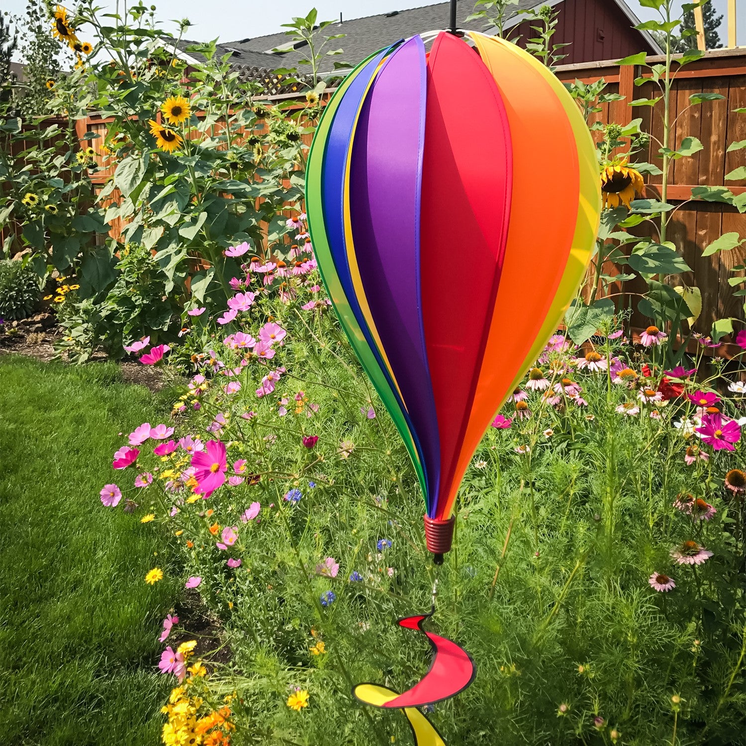 Vibrant Rainbow 12-Panel Hot Air Balloon spinner in a garden setting, showcasing colorful panels and twister tail spinning gracefully.