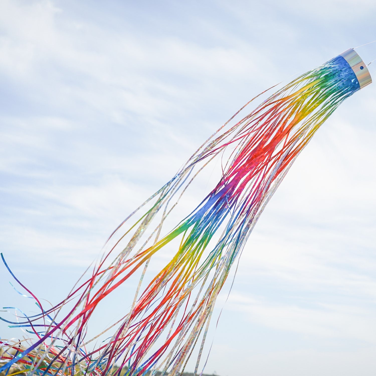 Rainbow 51-inch Mylar windsock fluttering in the breeze, reflecting sunlight with vibrant holographic colors for outdoor decoration.