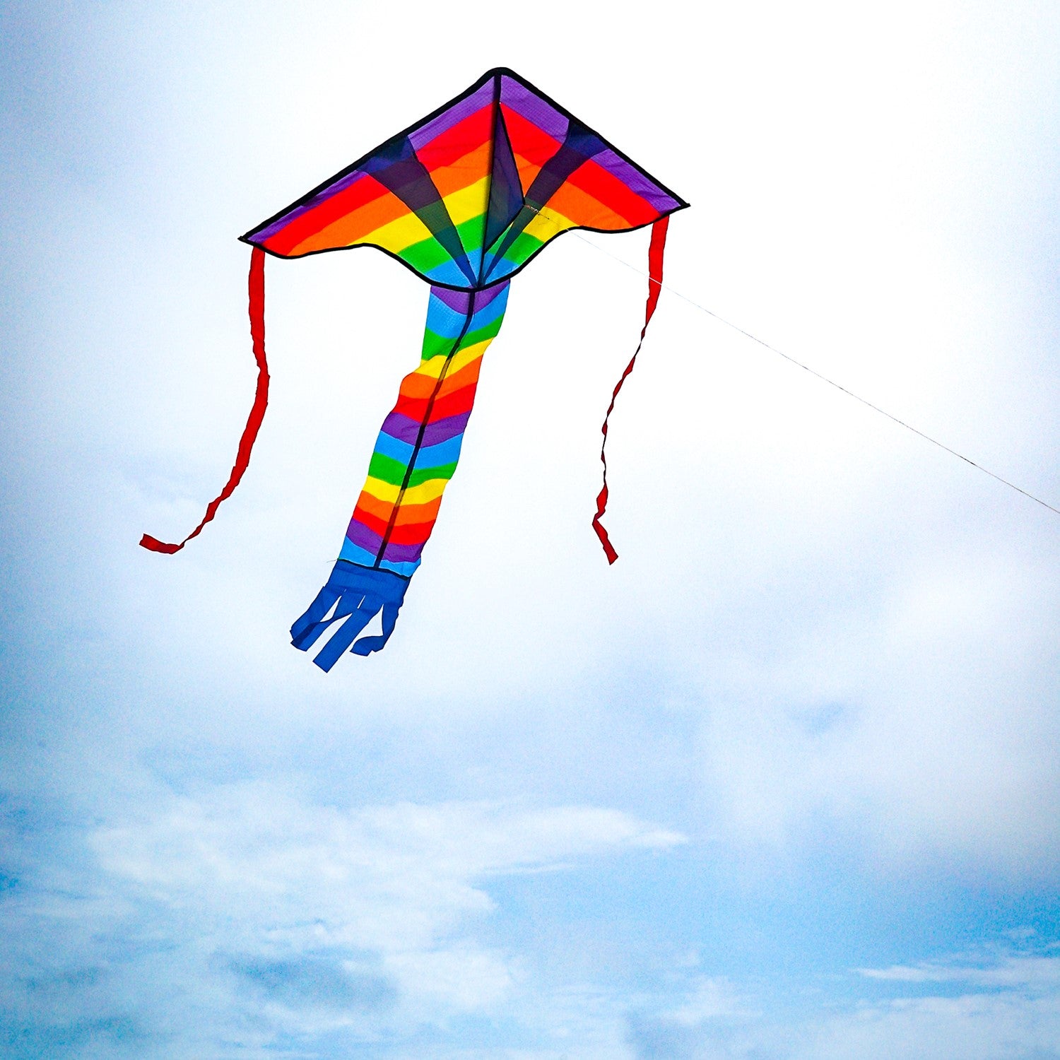 Rainbow Arrow Fly-Hi Kite soaring high in the sky, displaying colorful streamer tails, perfect for outdoor family fun.