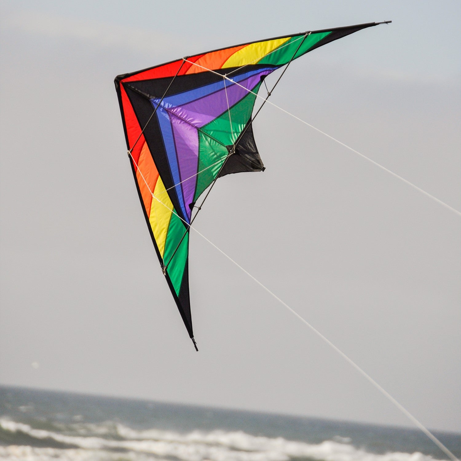 Rainbow Breeze 68" Sport Kite in rainbow color soaring high in a clear blue sky, showcasing its vibrant design and dual control lines.