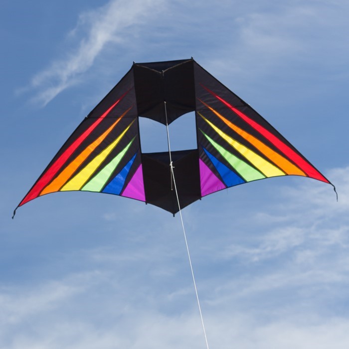 Rainbow Burst 6' Conyne Delta Kite featuring vibrant colors displayed in an outdoor setting with blue skies and fluffy clouds, ideal for family fun.