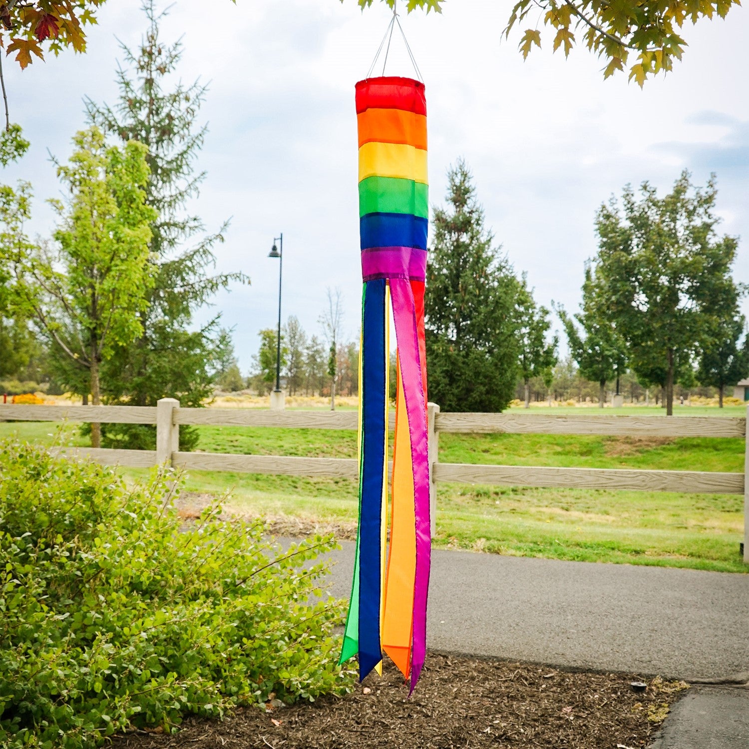Rainbow Column 50" windsock featuring vibrant rainbow hues and six matching tails, displayed elegantly in a garden setting.