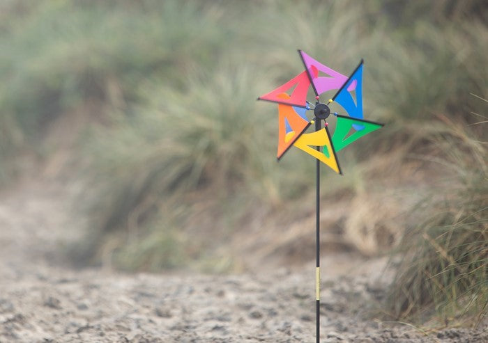 Rainbow Comet Ground Spinner with vibrant colors, displayed in a garden setting, gently spinning in the breeze on a fiberglass rod.