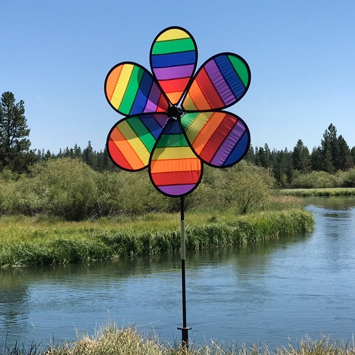 Colorful Rainbow Dazee Spinner featuring swirled petal design displayed in an outdoor garden, captivating attention as it spins in the breeze.