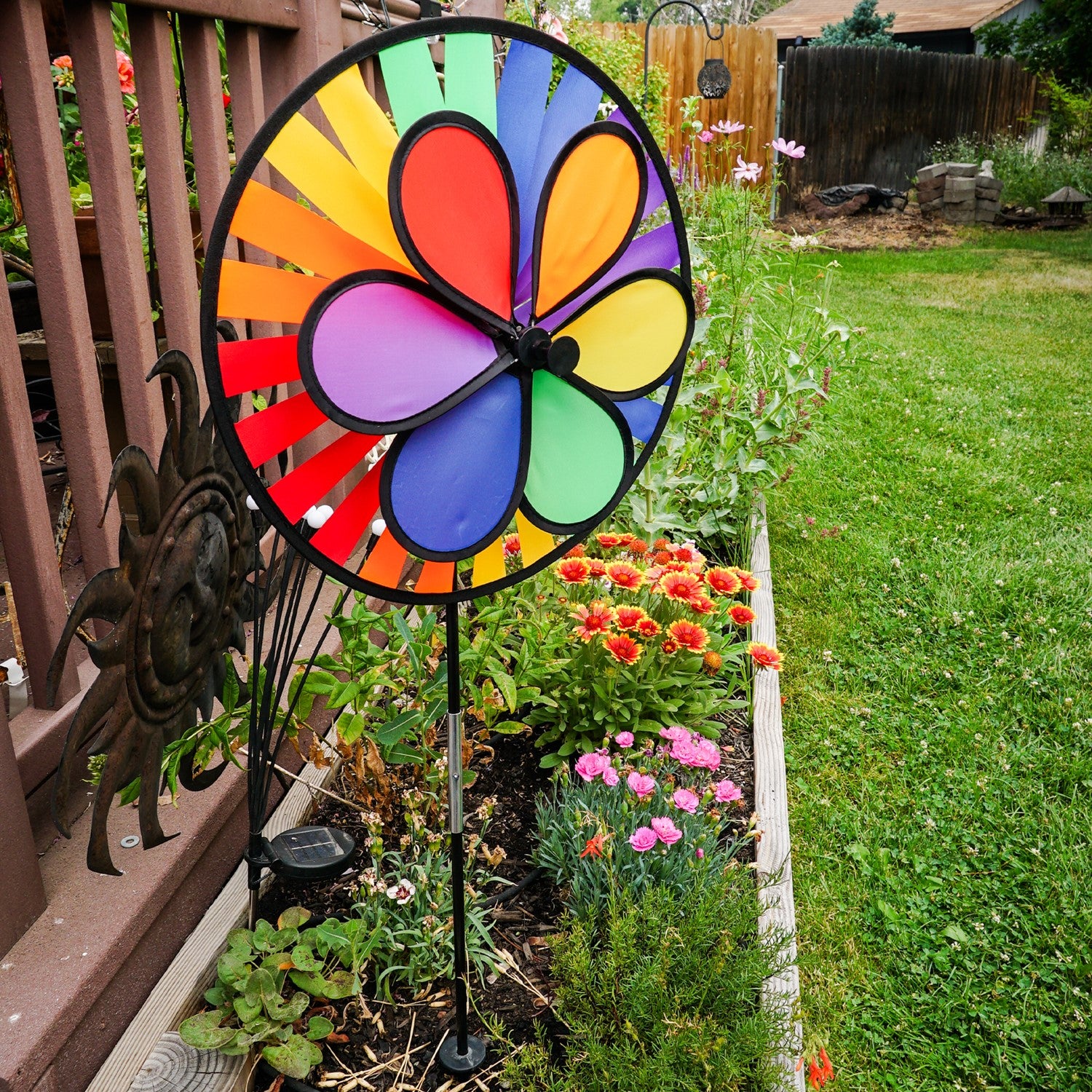 Rainbow Dazy Wheel garden spinner featuring a colorful design with a 12-inch petal top and a 15-inch spinner wheel, displayed outdoors.