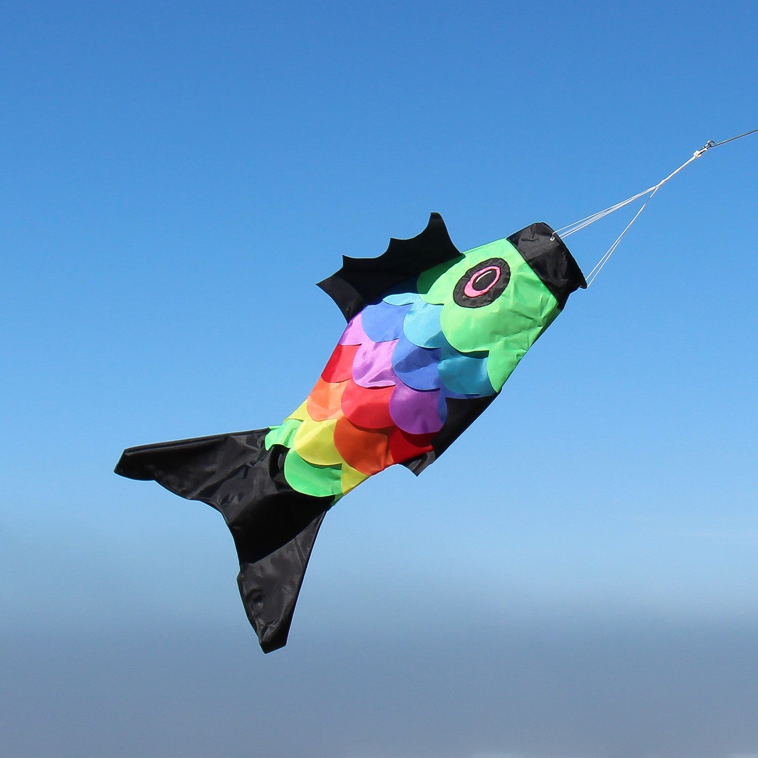 36-inch Rainbow Overlay Fish windsock featuring colorful embroidered scales displayed outdoors, fluttering in the breeze.