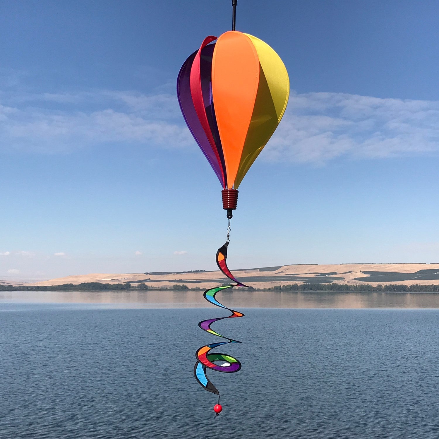 Rainbow-Panel Hot Air Balloon spinner measuring 26 inches with a vibrant rainbow design, beautifully displayed in an outdoor garden setting.
