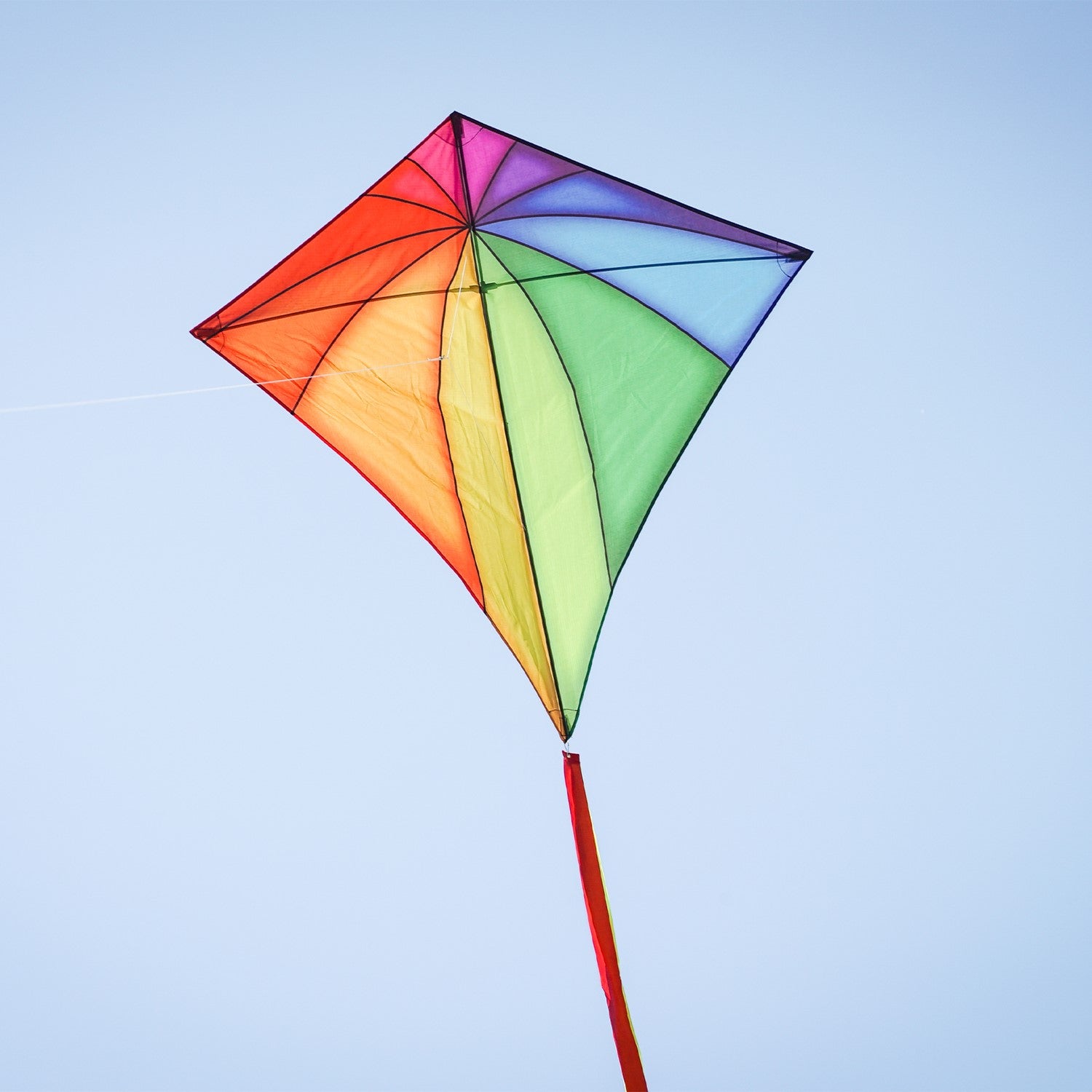 Rainbow Stained Glass 46" Diamond Kite soaring against a blue sky, showcasing vibrant colors and long, flowing tails during flight.