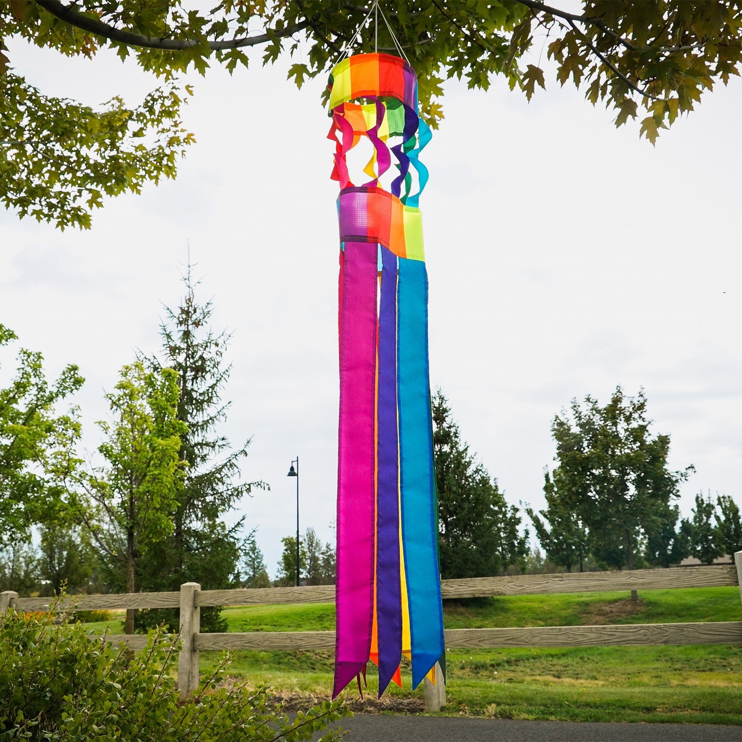 Visualize the Rainbow Twistair Windsock with its vibrant, swirling colors and eight flaring tails fluttering gracefully in the breeze, creating a joyful display.