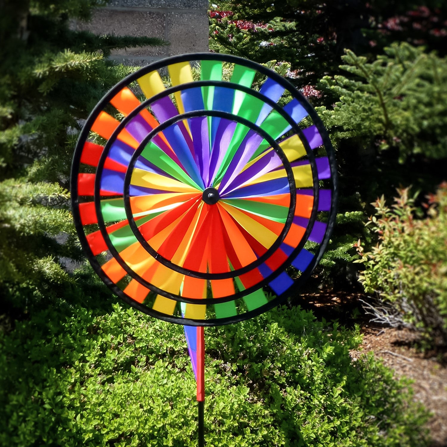 Rainbow Wind Sail Triple Wheel Spinner showcasing three spinning wheels in a rainbow spectrum, set against a clear blue sky with a pivoting pole for wind display.