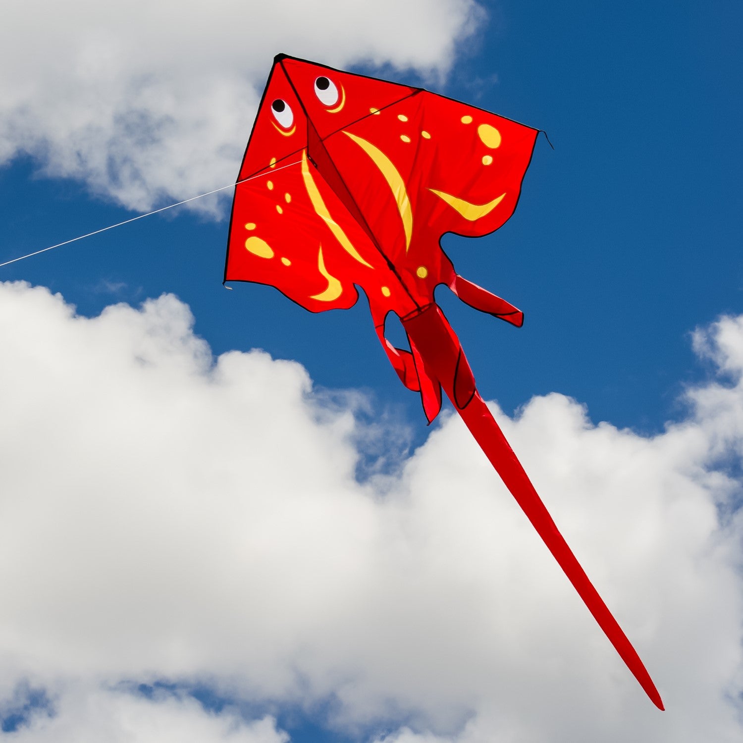 Red Stingray Kite soaring high against a bright blue sky, showcasing its vibrant colors and detailed applique design while flying peacefully.