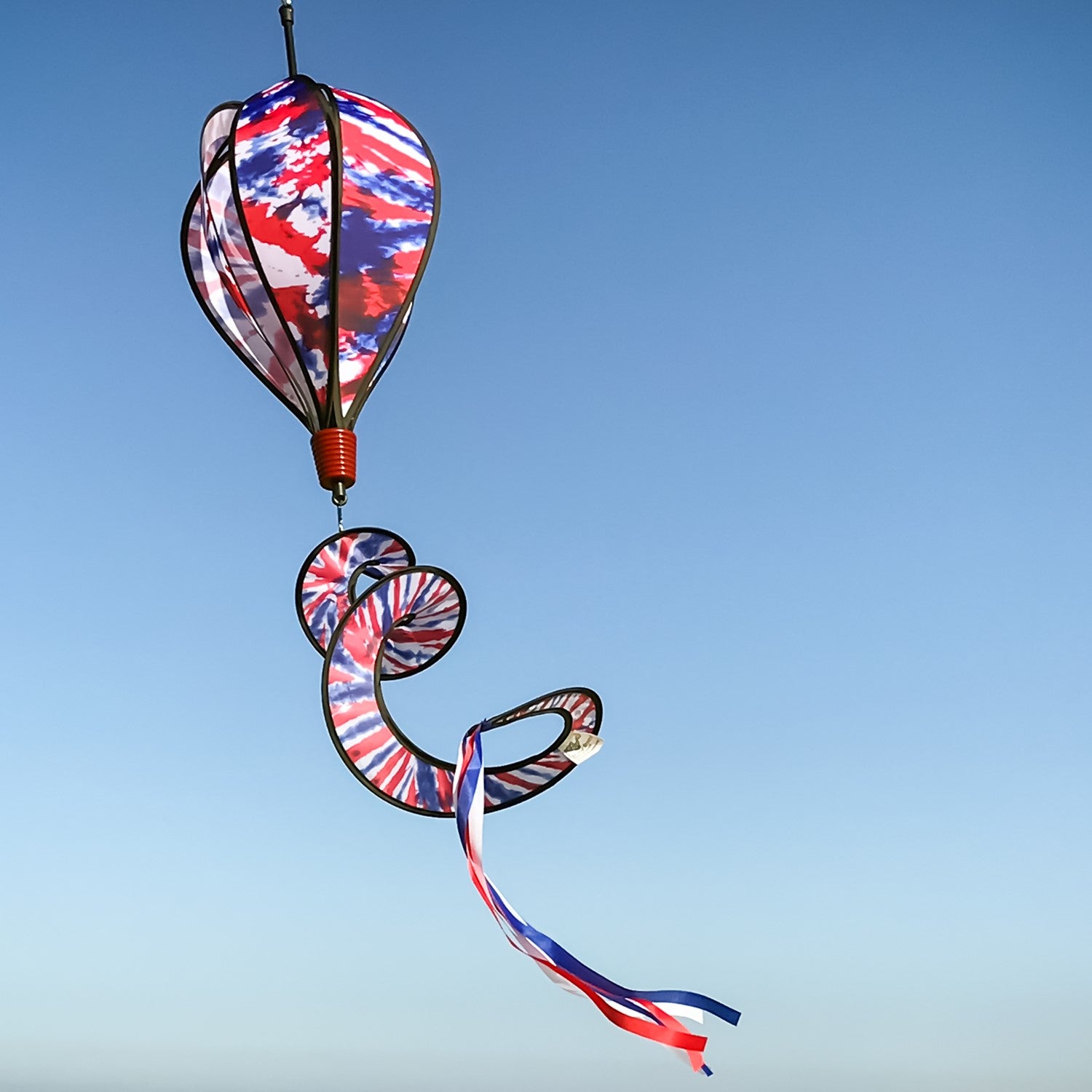 Red, White and Blue Tie Dye 6-Panel Hot Air Balloon spinner in an outdoor setting, showcasing its vibrant colors and delightful movement in the air.