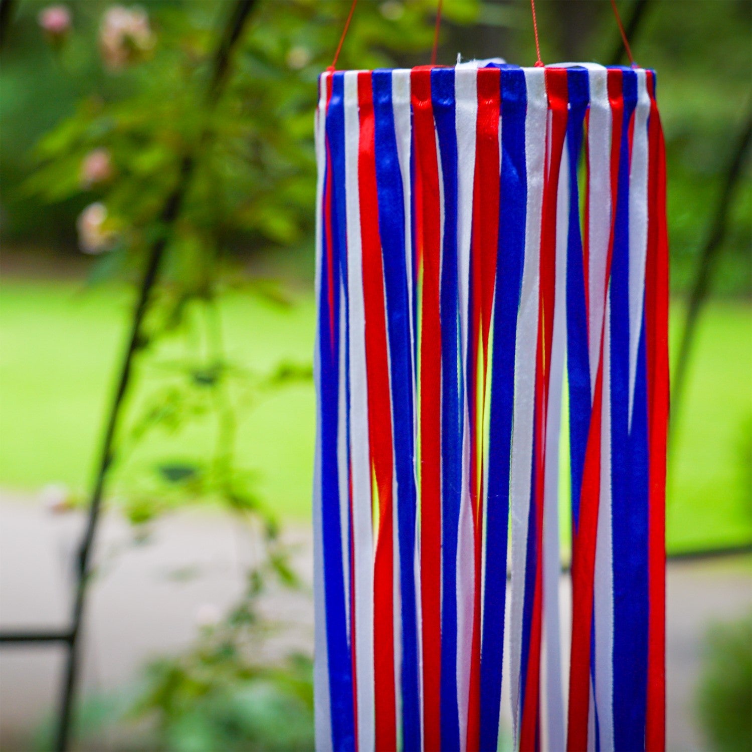 39\" Red, White & Blue Ribbon Windsock showcasing shiny satin ribbons in a festive garden setting, enhancing outdoor patriotic decor.
