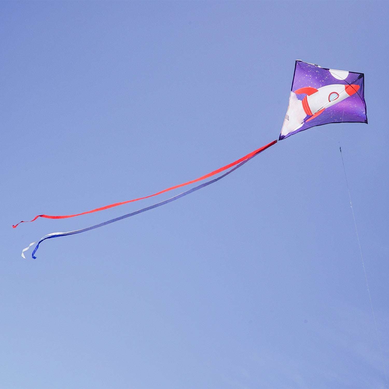 Rocket 30-inch Diamond Kite featuring a colorful rocket ship design with three attached tails, flying high against a blue sky.